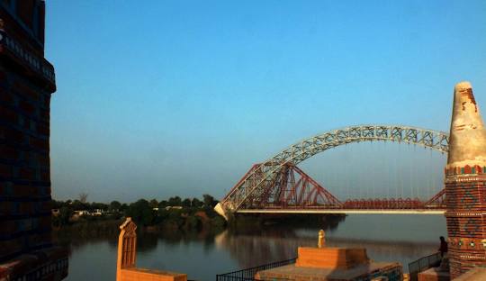 Indus River flowing through Sukkur with city skyline and bridge in background